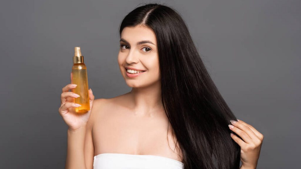 Woman with beautiful skin and strong hair, holding an oil bottle